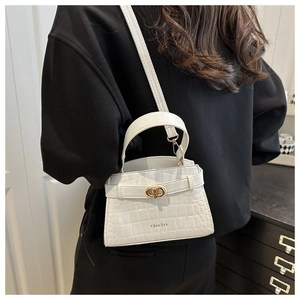 Detail of white crocodile pattern handbag with gold clasp shown in crossbody style