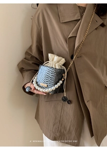 Detail of snake skin pattern bucket bag with pearl handle and gold chain strap