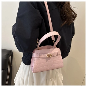 Detail of pink faux crocodile leather mini crossbody bag with gold buckle on model