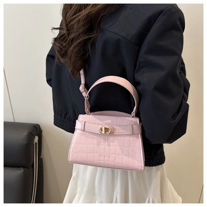 Detail of pink crocodile embossed leather handbag with gold clasp and brand lettering
