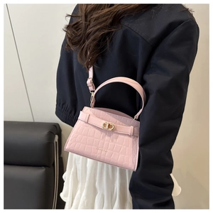 Close-up of pink crocodile-embossed handbag with gold hardware and brand embossing
