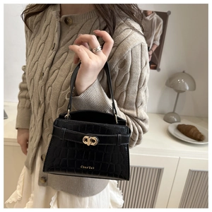 Close-up of black crocodile-embossed handbag with gold twist lock and brand logo detail