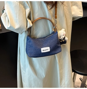 Blue denim half-moon bag with leather strap and cute teddy bear charm detail