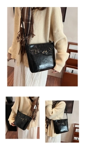 Detail of a chic black leather bucket bag with a golden buckle on a minimal background