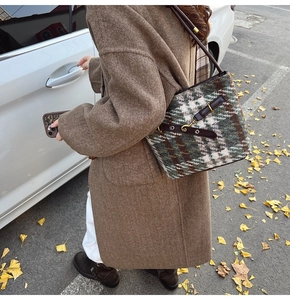 Detail of plaid wool shoulder bag with brown leather strap and metal buckle closure