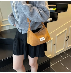 Detail of tan suede tote bag with leather strap and minimalist branded label on side