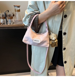Detailed shot of pink crescent underarm bag with cute teddy bear charm accessory