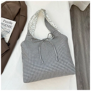 Detail of gingham canvas tote bag with bow tie and floral lining on a lifestyle background