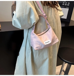 Detail of pink denim crossbody bag with adjustable strap and white woven label