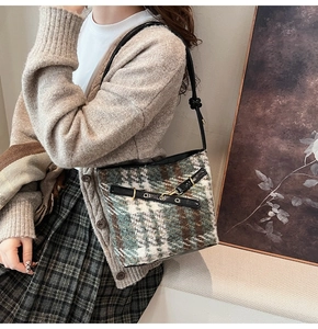 Detail of tweed bucket bag featuring green plaid pattern and black leather accents
