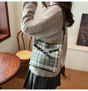 Close-up of checkered wool bucket bag featuring leather strap and gold buckle detail