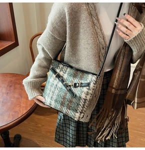 Detail of tweed bucket bag with blue plaid pattern and leather strap in a cozy setting