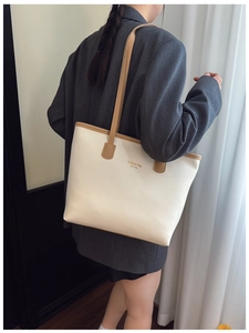 Detalle del bolso tote beige grande con asas caqui combinado con una chaqueta gris