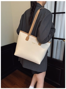 Detalle de bolso tote grande color crema con correas marrones al hombro de la modelo