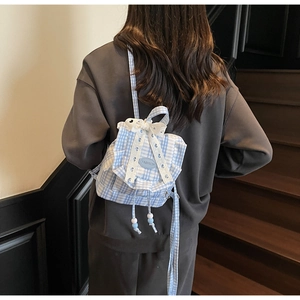 Detail of blue gingham backpack with white lace ruffles and bow decorations