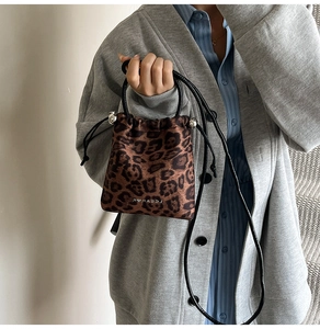 Détail du sac bandoulière à motif léopard avec fermeture à cordon et boucles métalliques