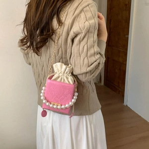Pink faux snakeskin box bag with pearl handle and gold chain strap worn by a model