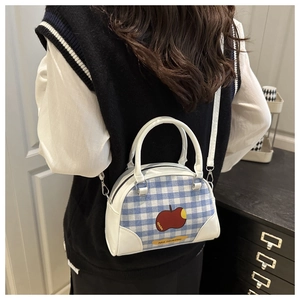 Detail showing a mini blue plaid apple bowling bag worn with a crossbody strap