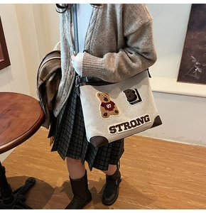 Dettaglio borsa in tela beige con ricamo orso, toppa B e bordi rinforzati in pelle marrone