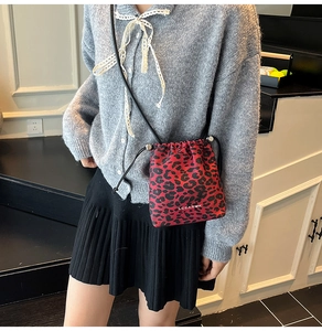 Sac seau léopard rouge avec cordon de serrage et fine bandoulière porté par un mannequin