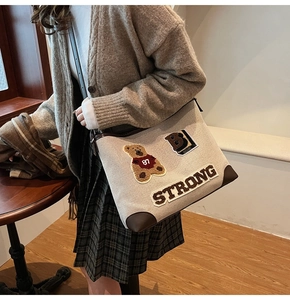 Dettaglio della borsa tote in tela beige con ricamo a orsetto e angoli in pelle marrone