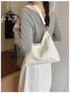 Detail of white patent leather shoulder bag with FASHION BAGS text and gold hardware