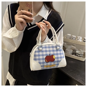 Close-up of blue and white checkered shell handbag with red apple print and silver hardware