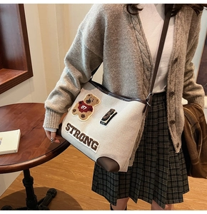 Dettaglio borsa tote in tela vintage con toppa a forma di orso e ricamo di lettere forti