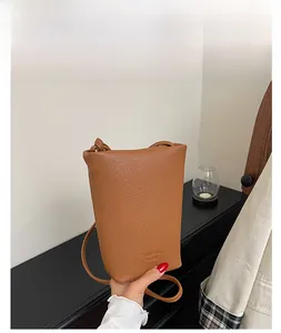 Detail of a brown lychee pattern leather bucket bag showing embossed logo and texture