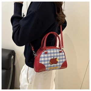 Detail view of a red and blue checkered crossbody bag with apple graphics and strap