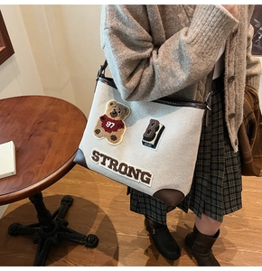 Dettaglio della borsa tote in tela beige con ricamo di orsetto e finiture in cuoio