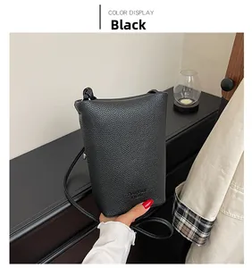 Detail of black pebbled leather bucket bag on a display table with a glass candle holder