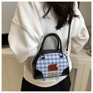 Detail of vintage plaid square bag with apple print shown on model in minimal setting