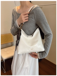 Detail of cream white faux leather hobo shoulder bag with fashion text and polka dot scarf