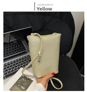 Close-up of yellow pebbled leather crossbody bag with knot strap and golden finish