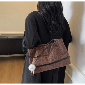 Detailed side view of leopard print canvas tote bag with black straps and plush charm