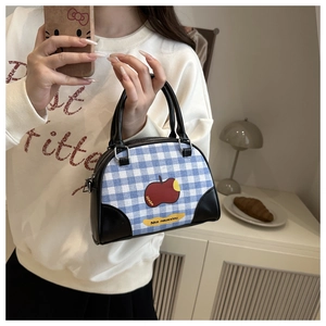 Detail of blue plaid bowling bag with red apple print and black leather handles
