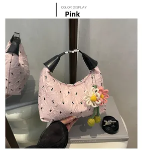 Detail of pink ruffled handbag with black bow prints and woven flower charm accessory
