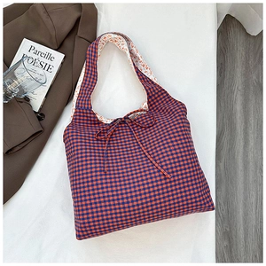 Close-up of reversible checkered tote bag with floral lining and delicate bow tie detail
