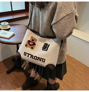 Dettaglio del ricamo dell'orso carino e della scritta STRONG sulla borsa tote in tela