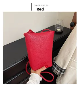 Detail view of red lychee textured bucket bag with branded stamp and slender strap
