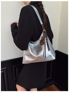 Detailed shot of silver metallic hobo bag with unique art pendant and fashion branding