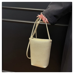 Close-up of cream pebble leather mini crossbody bag featuring embossed logo detail