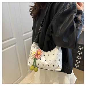 Detail of white pleated handbag featuring decorative knit flowers and patterned texture
