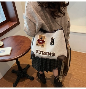 Dettaglio del ricamo su borsa tote in tela avorio con angoli rinforzati in pelle marrone