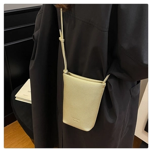 Detail of champagne gold mini crossbody phone bag with pebble leather texture and embossing