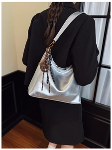 Detail of silver metallic tote bag with fashion tag on a model in a black suit