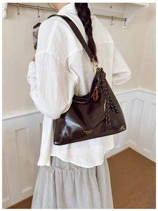 Detail view of large dark brown hobo bag with gold logo and stylish charm on model