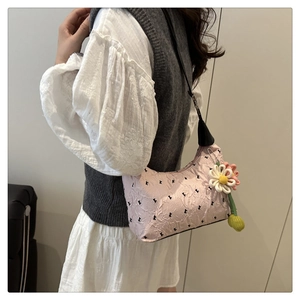 Dettaglio borsa a spalla plissettata rosa con ciondolo a margherita e tracolla nera