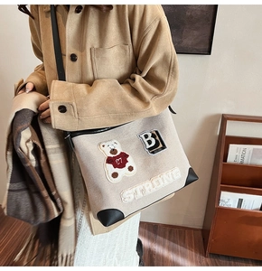 Dettaglio della borsa tote in tela con ricamo di orso e angoli in pelle rinforzati